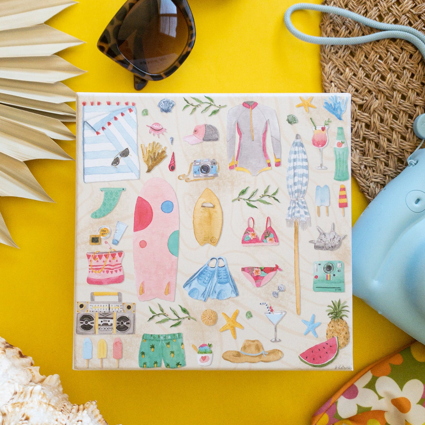 Puzzle box surrounded by camera, bikini, shell, sunglasses, hat, and palm